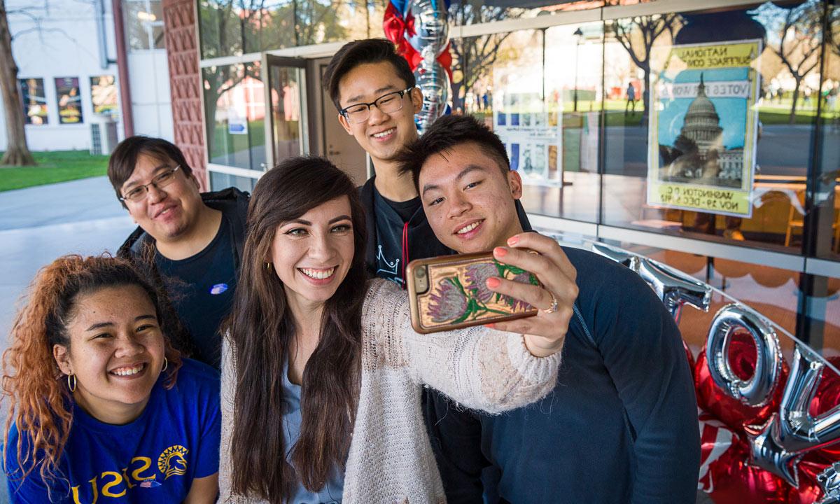 菠菜网lol正规平台 students huddling together for a selfie at a voting center.